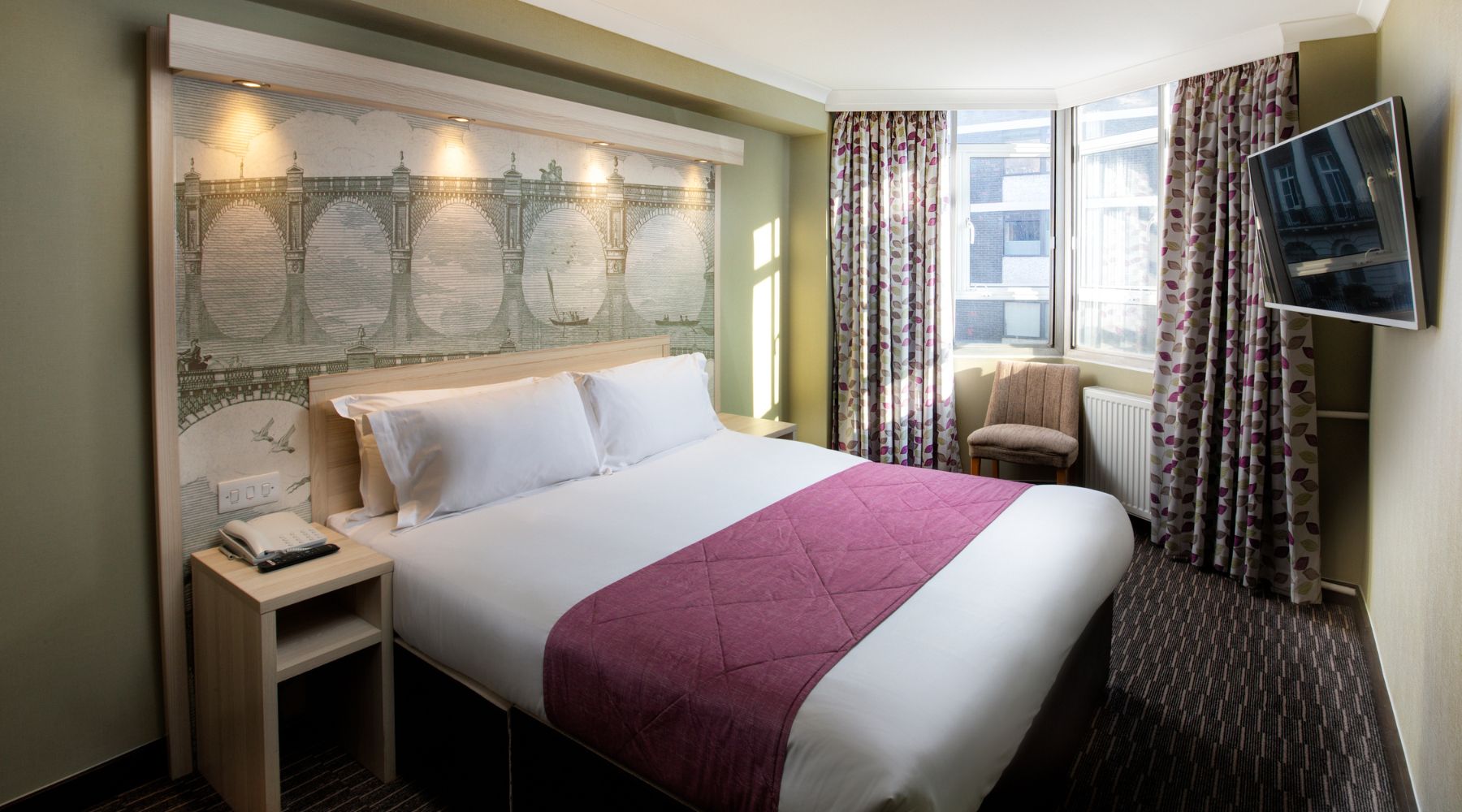 President hotel room near Euston Station with double bed, wall art, & natural light, ideal for stays close to London attractions.